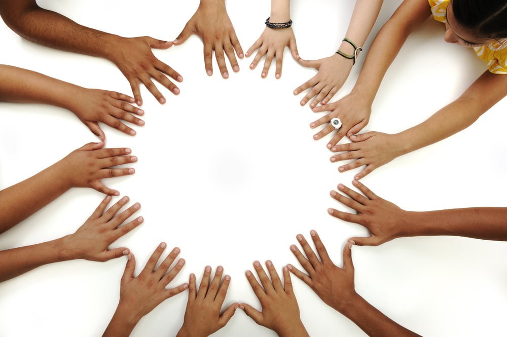 Diverse group of educators enthusiastically raise hands during special education professional development, symbolizing collective commitment to inclusive teaching practices.