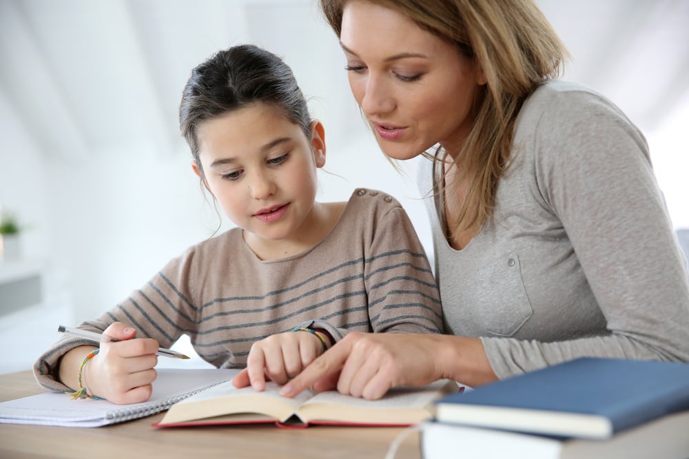 Educator implements behavior management strategies with a small group of diverse learners, demonstrating positive reinforcement techniques in an inclusive classroom environment. Students actively participate in grade-level content with appropriate accommodations.