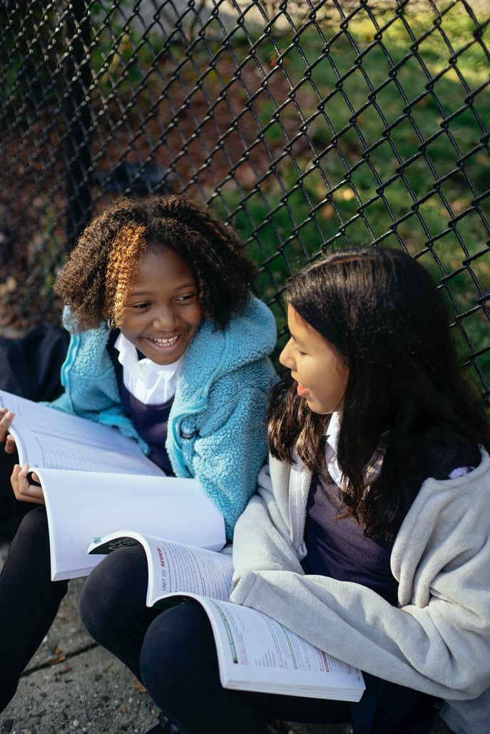 student girls reading a book together at school