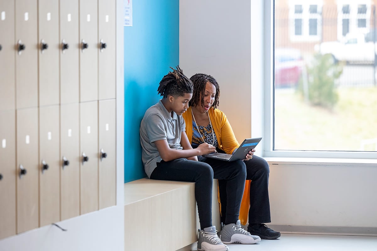 Photo of a student and adult sitting together working on a computer